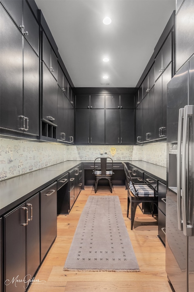 kitchen featuring light wood-style floors, dark cabinets, and stainless steel fridge with ice dispenser