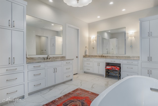 full bath with marble finish floor, a freestanding bath, a sink, and recessed lighting