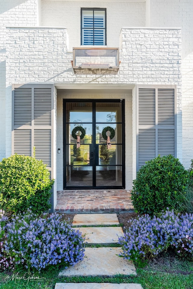 doorway to property featuring french doors and brick siding