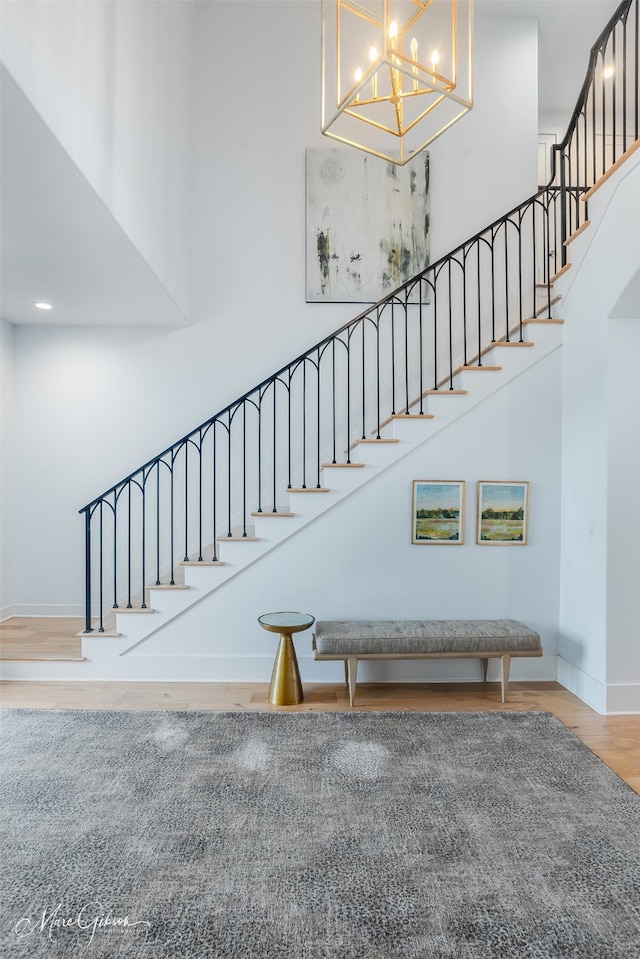 staircase featuring a high ceiling, baseboards, and wood finished floors