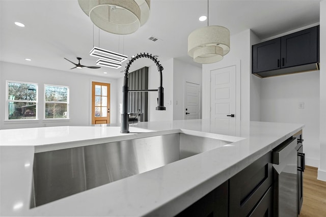 kitchen with ceiling fan, sink, hanging light fixtures, and light hardwood / wood-style flooring