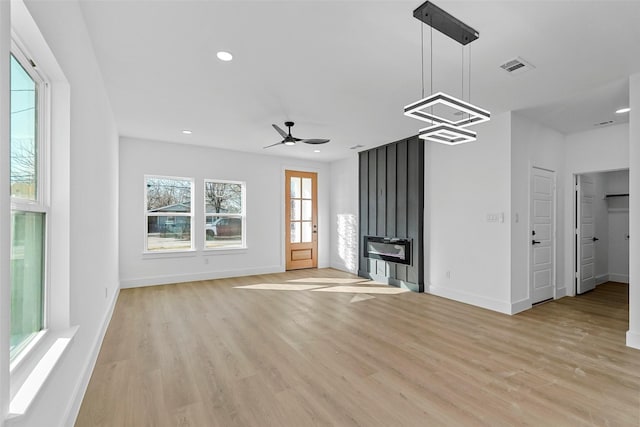 unfurnished living room with light hardwood / wood-style floors and ceiling fan with notable chandelier