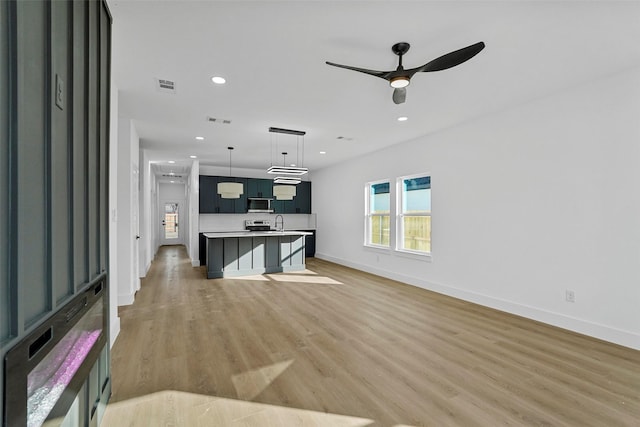 living room with ceiling fan, sink, and light hardwood / wood-style floors