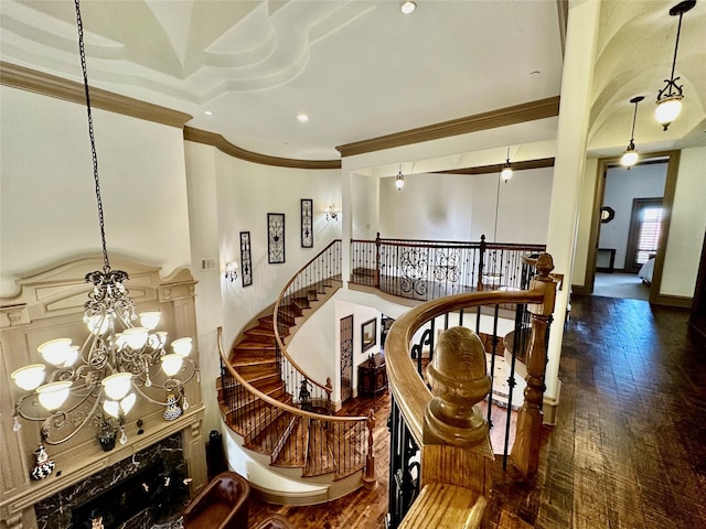 stairs with an inviting chandelier, ornamental molding, and wood-type flooring