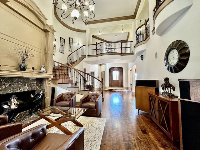 foyer entrance with a chandelier, ornamental molding, dark hardwood / wood-style floors, a premium fireplace, and a high ceiling