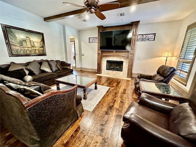 living room featuring a wealth of natural light, a fireplace, beamed ceiling, wood-type flooring, and ceiling fan