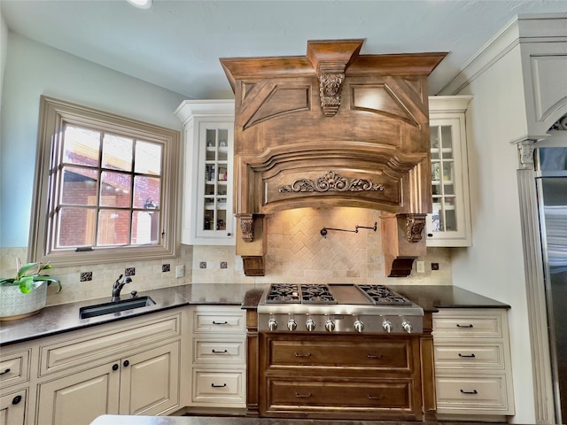 kitchen featuring tasteful backsplash, cream cabinets, stainless steel gas cooktop, and sink