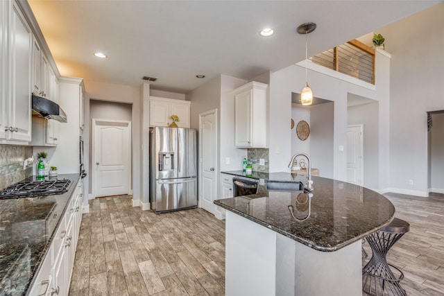 kitchen featuring white cabinetry, sink, dark stone countertops, appliances with stainless steel finishes, and light wood-type flooring