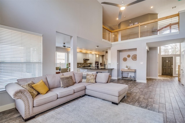 living room with hardwood / wood-style flooring, ceiling fan, and a high ceiling