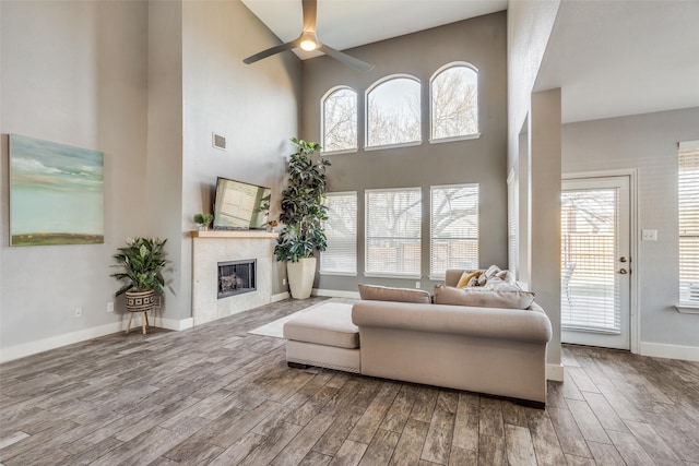 living room featuring a high ceiling, ceiling fan, and a healthy amount of sunlight