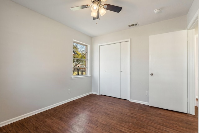 unfurnished bedroom featuring ceiling fan, dark hardwood / wood-style floors, and a closet