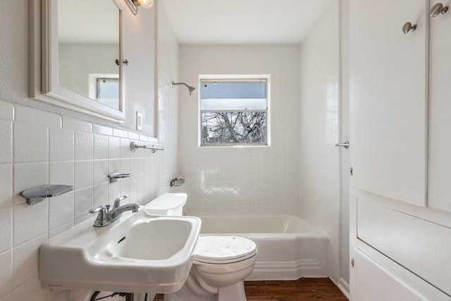 full bathroom with tile walls, sink, tiled shower / bath combo, hardwood / wood-style flooring, and toilet