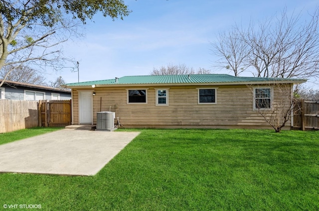 rear view of property featuring central AC unit, a patio area, and a lawn