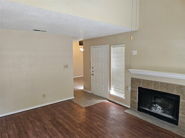 unfurnished living room featuring a tile fireplace, a textured ceiling, and hardwood / wood-style flooring