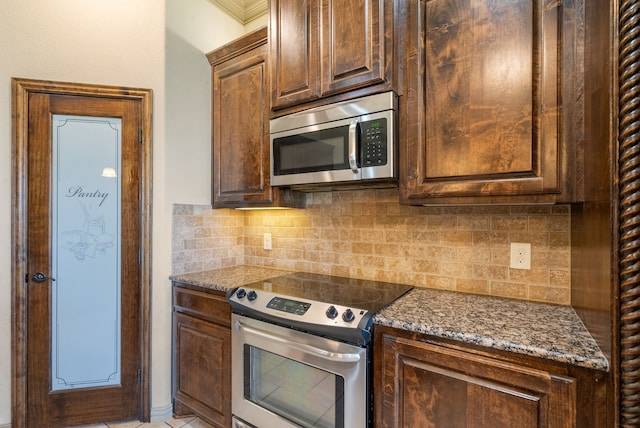 kitchen featuring stainless steel appliances, dark stone countertops, and decorative backsplash