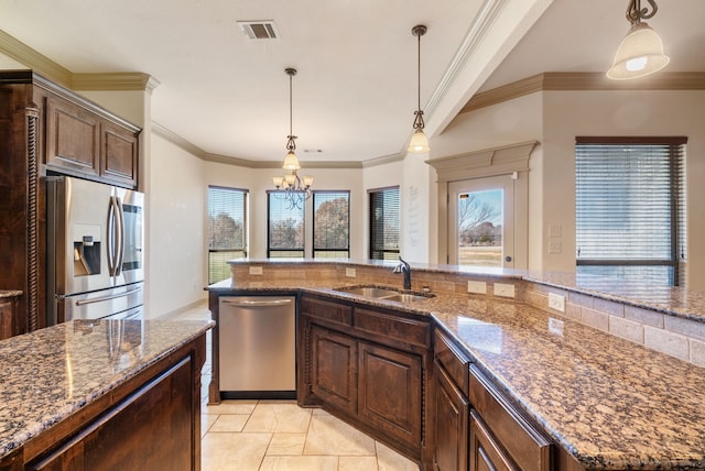 kitchen with a chandelier, a center island with sink, appliances with stainless steel finishes, pendant lighting, and sink