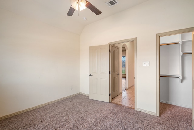 unfurnished bedroom featuring lofted ceiling, a closet, ceiling fan, and light colored carpet