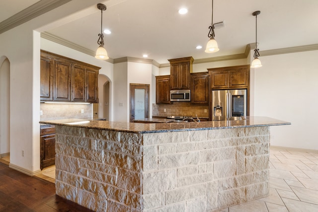 kitchen with stainless steel appliances, a large island, dark stone counters, and hanging light fixtures