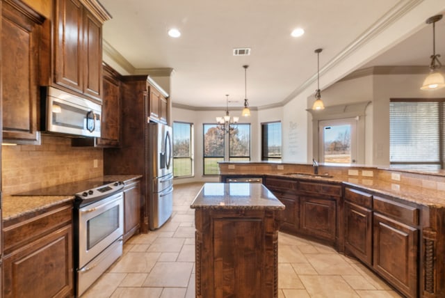 kitchen with sink, a kitchen island, hanging light fixtures, and appliances with stainless steel finishes