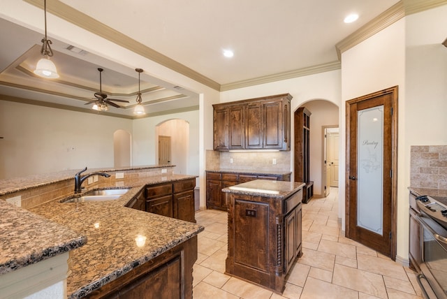 kitchen with decorative light fixtures, a kitchen island, stainless steel electric range, a tray ceiling, and sink