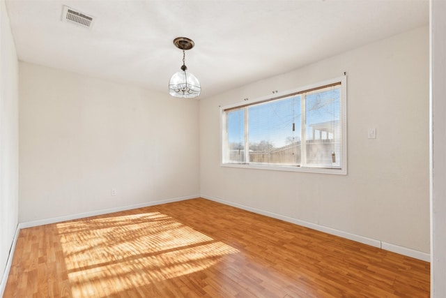 empty room featuring hardwood / wood-style flooring and a notable chandelier