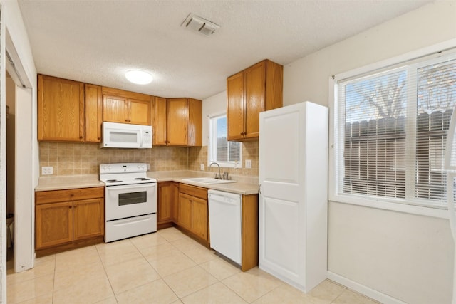 kitchen with white appliances, backsplash, sink, a textured ceiling, and plenty of natural light