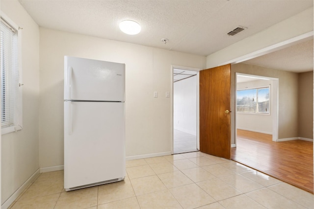 kitchen with white refrigerator, light tile patterned floors, and a textured ceiling