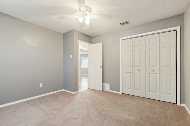 unfurnished bedroom with ceiling fan, light colored carpet, a textured ceiling, and a closet