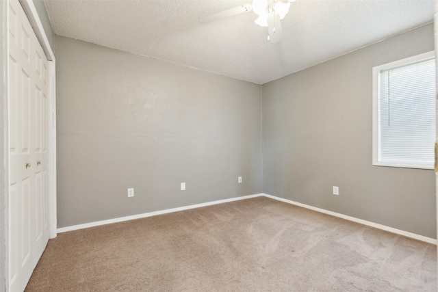 carpeted spare room featuring a textured ceiling and ceiling fan