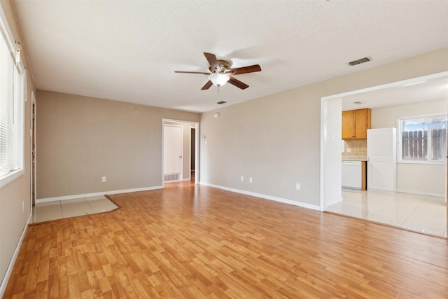 unfurnished room with a textured ceiling, light wood-type flooring, and ceiling fan