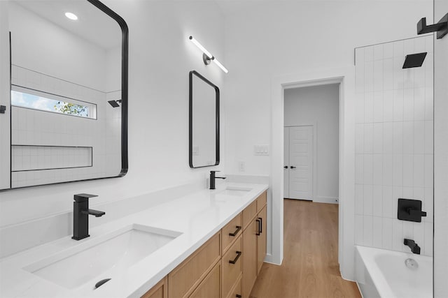 bathroom featuring hardwood / wood-style floors, tiled shower / bath combo, and vanity