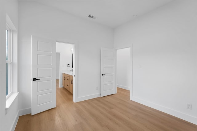 unfurnished bedroom featuring light wood-type flooring and connected bathroom