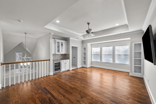 unfurnished living room with hardwood / wood-style floors, ceiling fan with notable chandelier, a raised ceiling, and beverage cooler