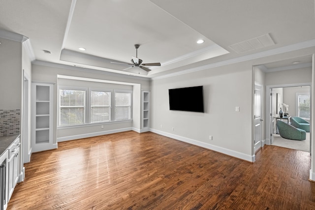 unfurnished living room with hardwood / wood-style floors, a tray ceiling, plenty of natural light, and crown molding