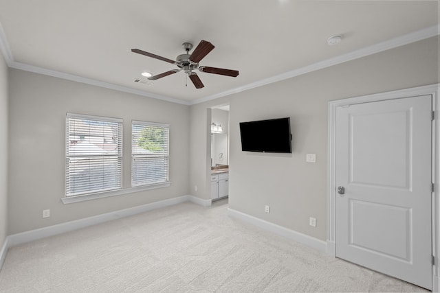 interior space with ceiling fan, light colored carpet, ornamental molding, and connected bathroom