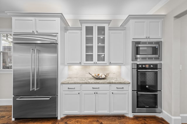 kitchen featuring built in appliances, white cabinetry, and light stone counters