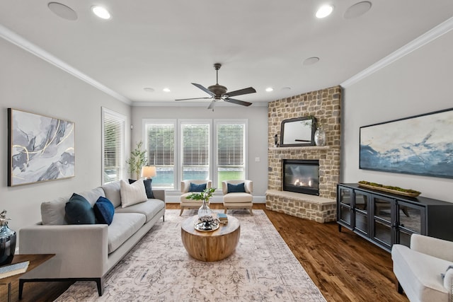 living room with a fireplace, dark hardwood / wood-style flooring, ceiling fan, and crown molding