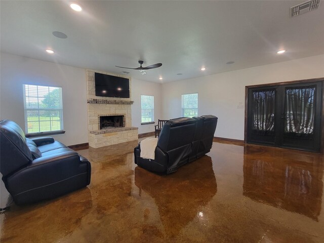 living room with a stone fireplace and ceiling fan