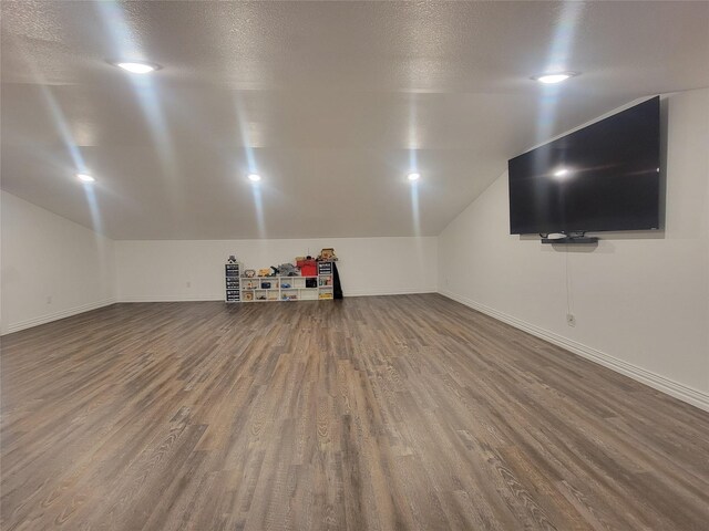 interior space with a textured ceiling, hardwood / wood-style flooring, and vaulted ceiling