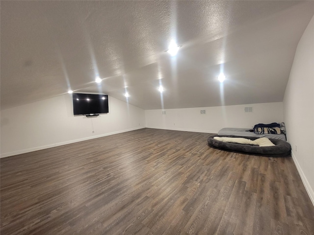 additional living space featuring dark hardwood / wood-style flooring, lofted ceiling, and a textured ceiling