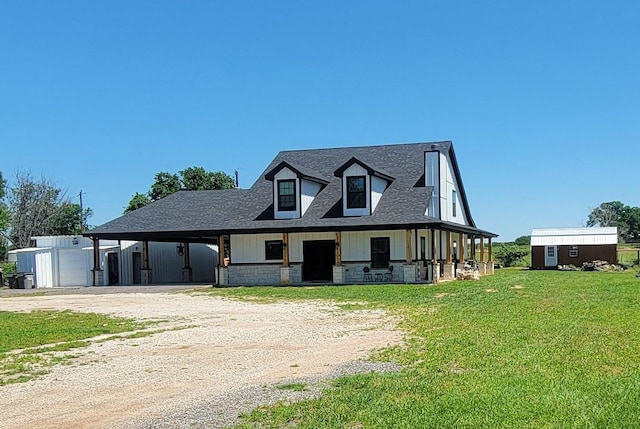 view of front of home with covered porch, a carport, an outbuilding, and a front lawn