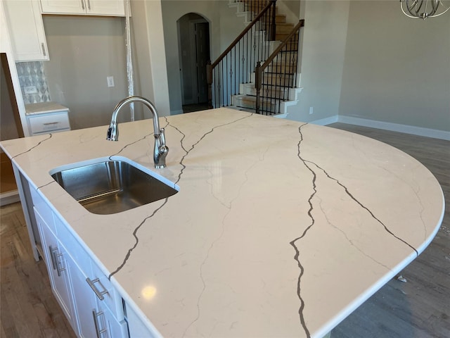 kitchen with sink, white cabinets, light stone counters, tasteful backsplash, and dark wood-type flooring