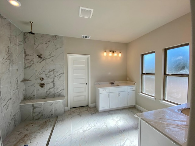 bathroom featuring tiled shower, a wealth of natural light, and vanity