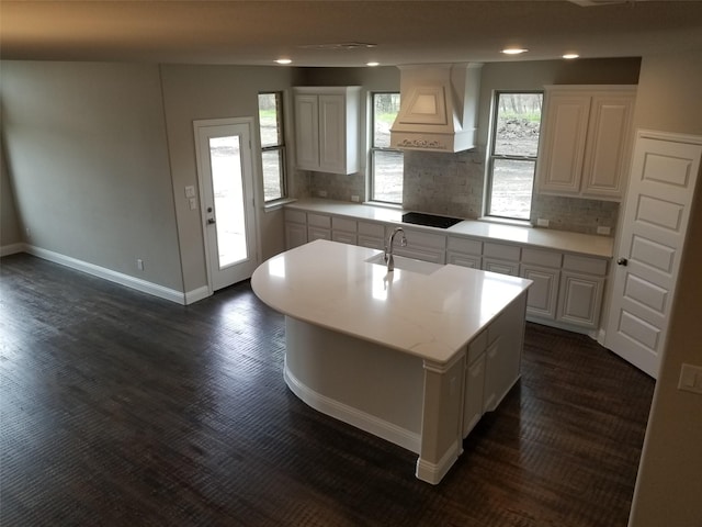 kitchen with white cabinets, backsplash, and a center island with sink