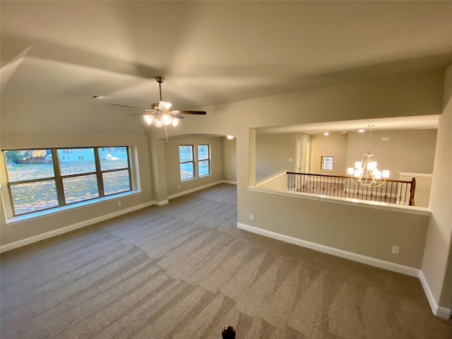 unfurnished living room with ceiling fan with notable chandelier and carpet