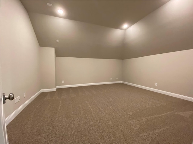 bonus room featuring lofted ceiling and dark colored carpet