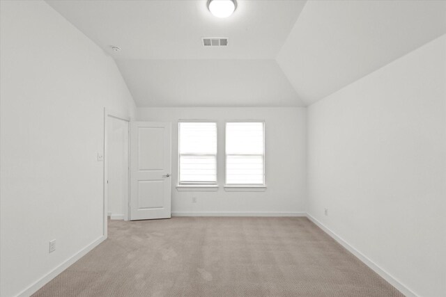 carpeted empty room featuring lofted ceiling