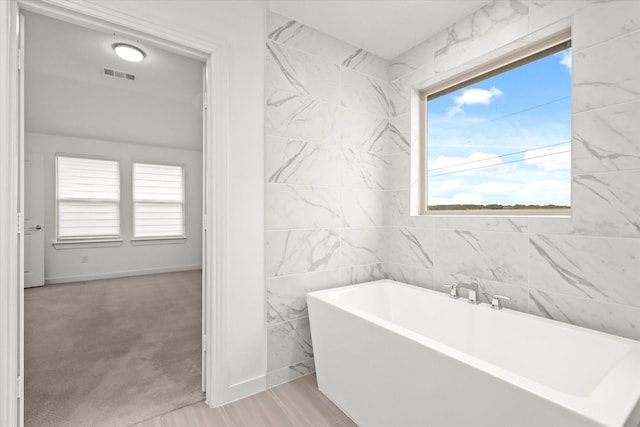 bathroom with a tub, a wealth of natural light, and hardwood / wood-style floors