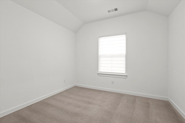 carpeted empty room featuring vaulted ceiling