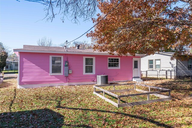 rear view of property featuring central air condition unit and a yard